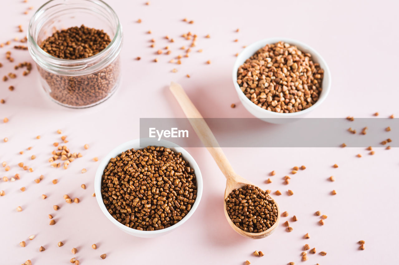 Raw buckwheat tea in a bowl and wooden spoon and buckwheat on the table