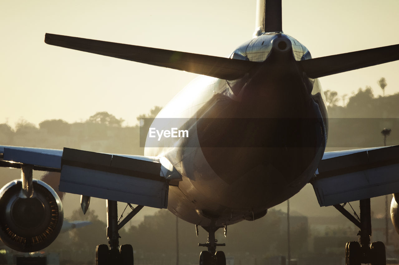Close-up of airplane at airport during sunset