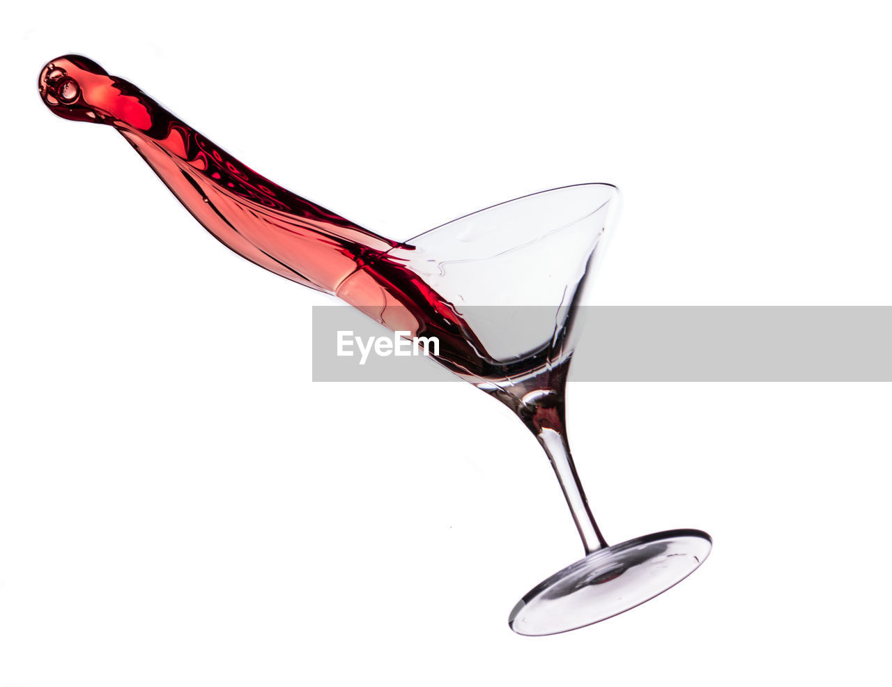 Close up of red wine spilling against white background