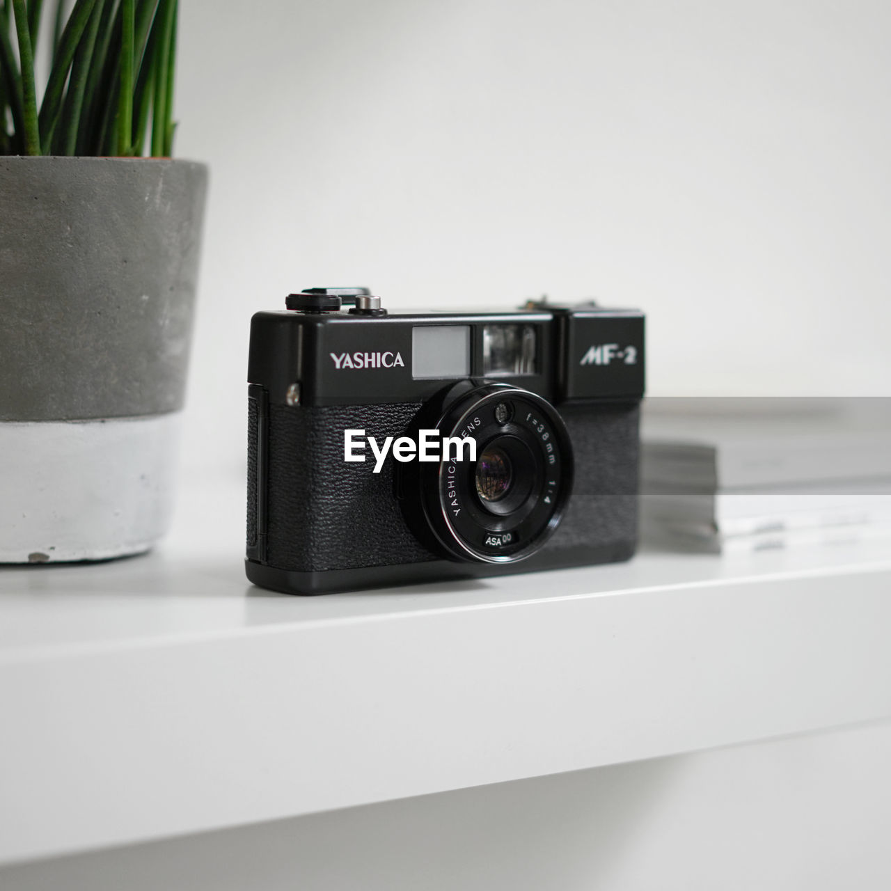 CLOSE-UP OF CAMERA ON TABLE WITH EYEGLASSES AND WHITE