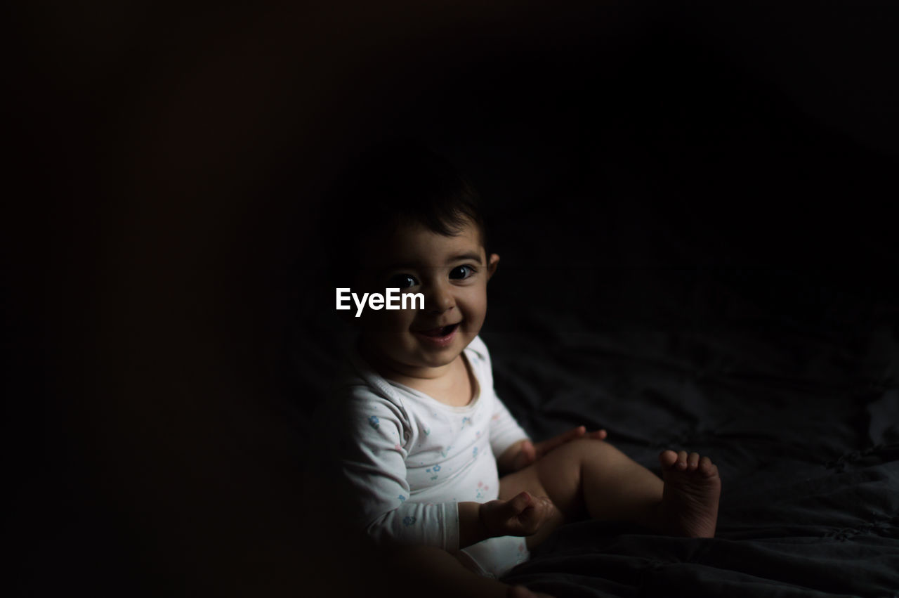 Baby smiling in bed with sunset light