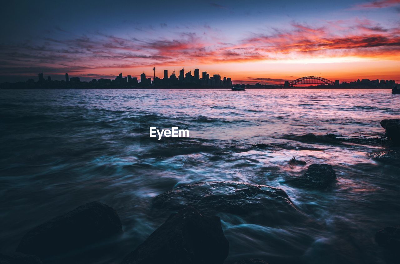 Scenic view of seascape by city during sunset