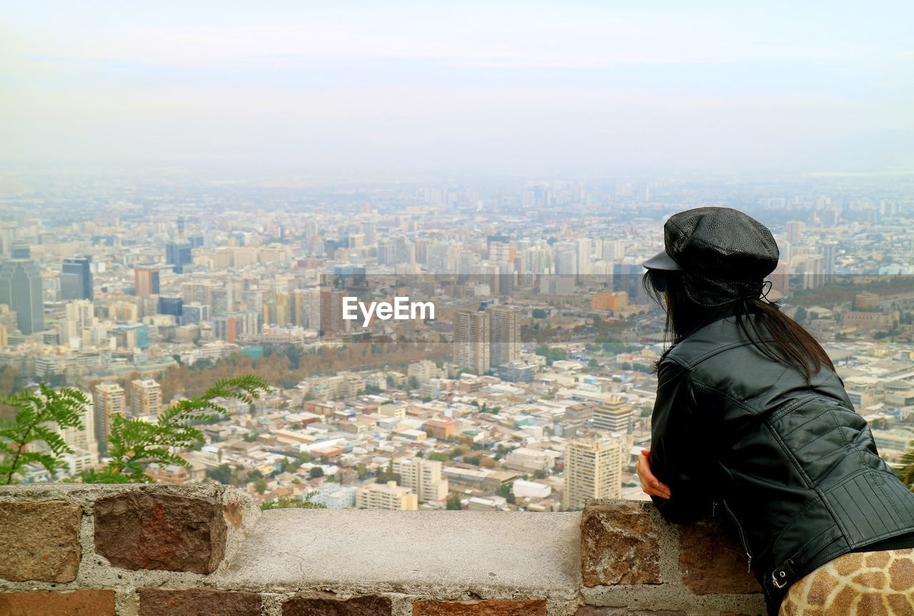 Side view of woman wearing leather jacket looking at cityscape