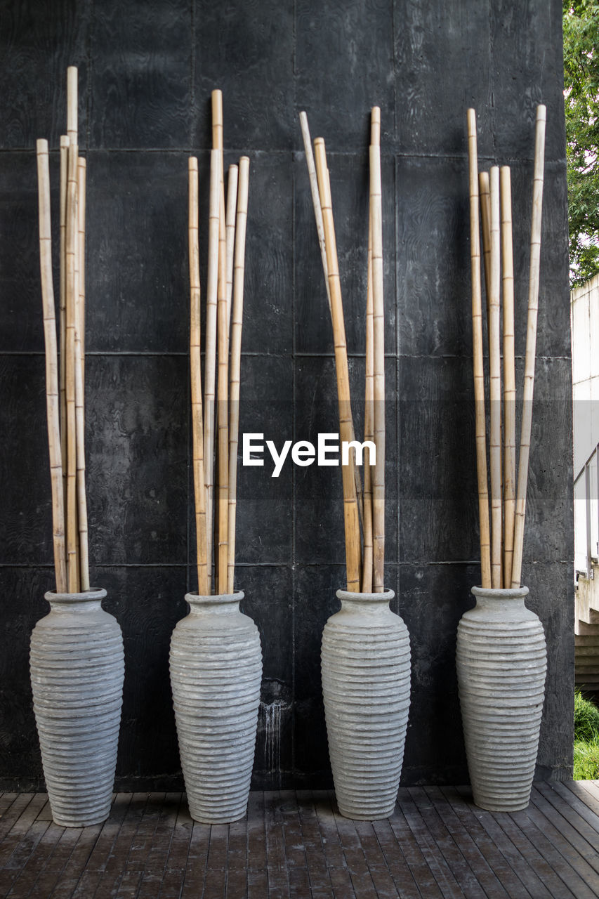 Bamboos on vases against wall