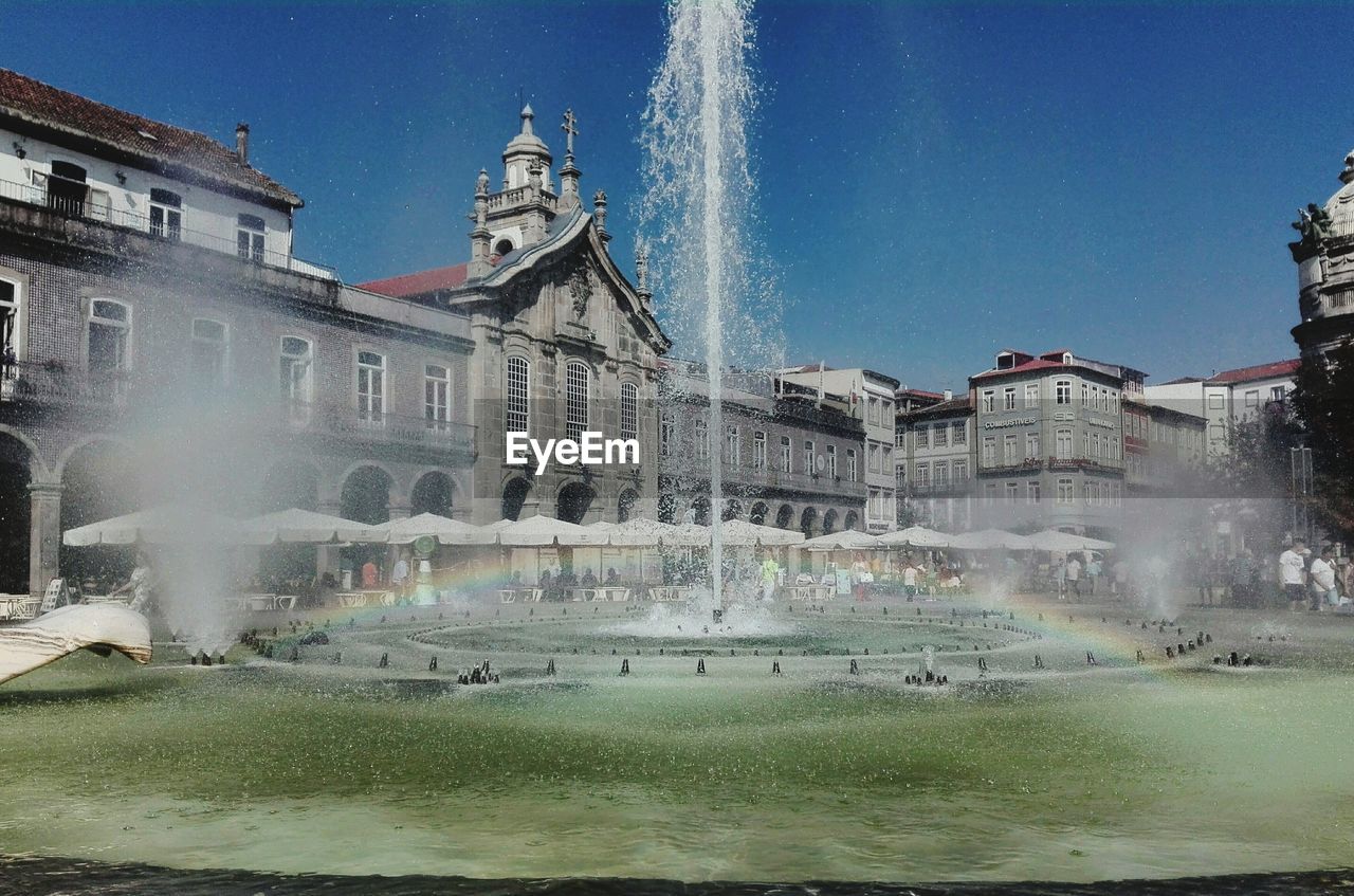 WATER FOUNTAIN IN CITY AGAINST SKY