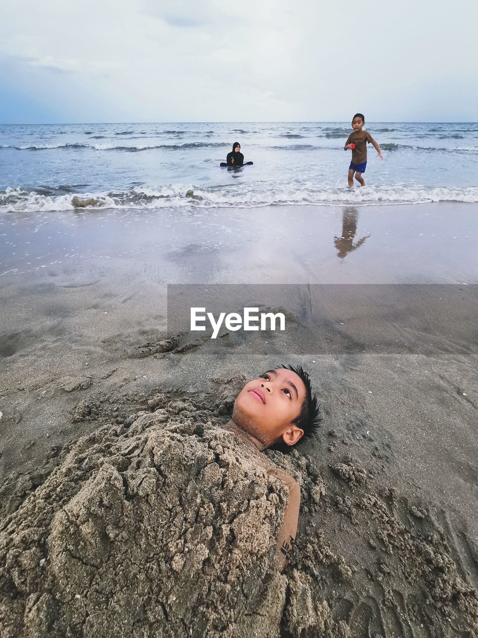 Children on beach against sky