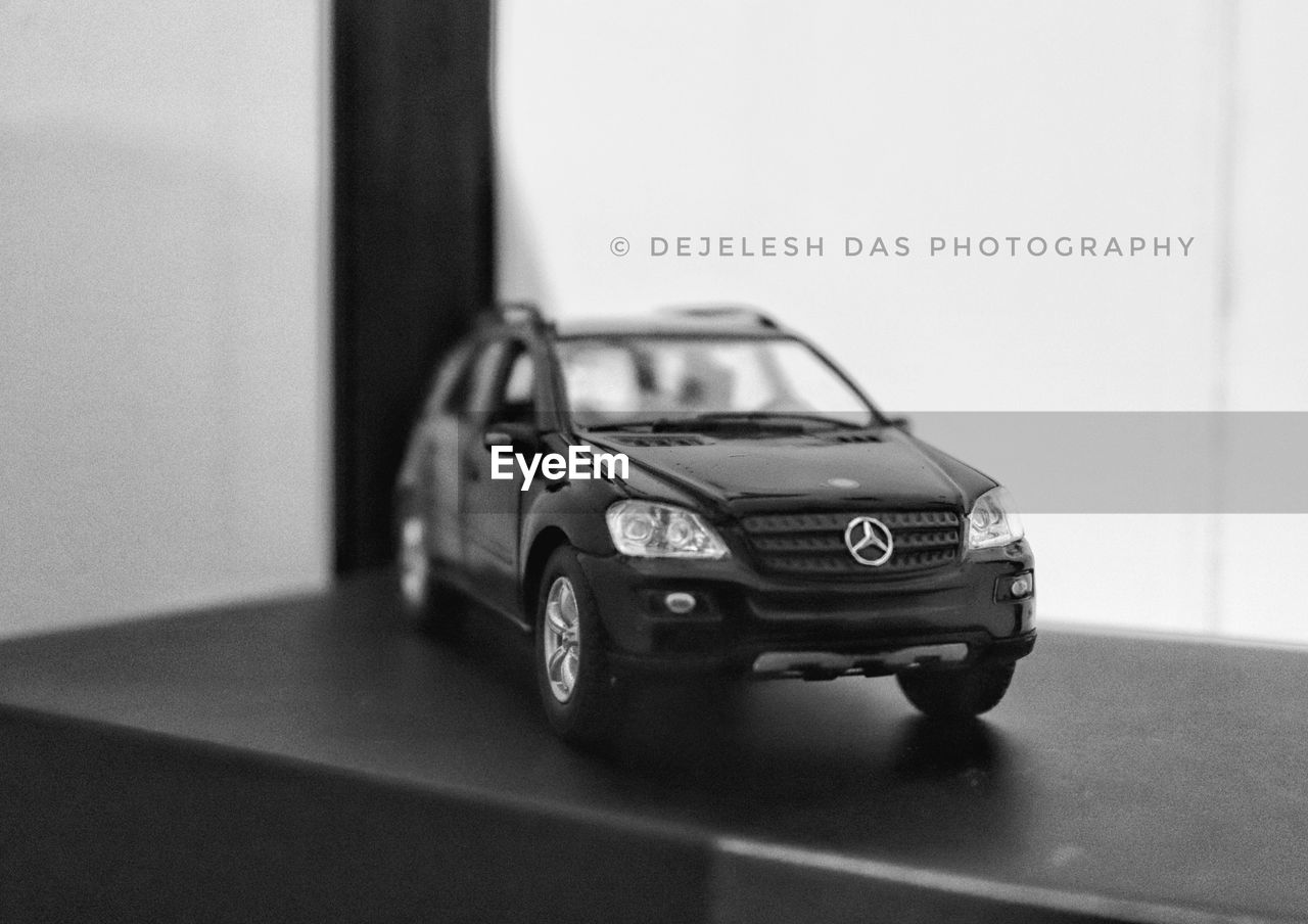 car, vehicle, automobile, mode of transportation, motor vehicle, land vehicle, transportation, luxury vehicle, black and white, indoors, sport utility vehicle, text, monochrome, wheel, automotive exterior, no people, monochrome photography, toy car