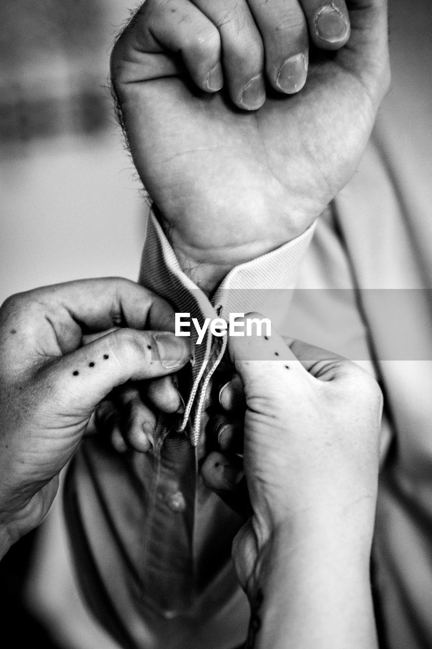 Cropped woman buttoning man handcuffs at home 