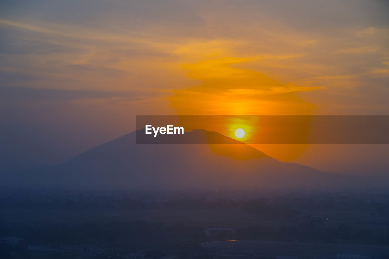 SCENIC VIEW OF SILHOUETTE MOUNTAIN AGAINST ORANGE SKY