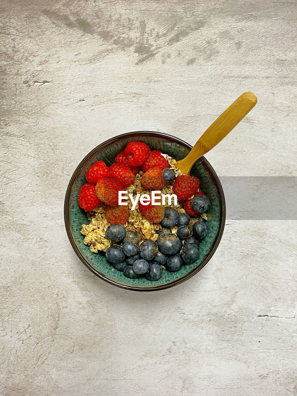 Overhead shot of raspberries, blueberries, granola in a bowl