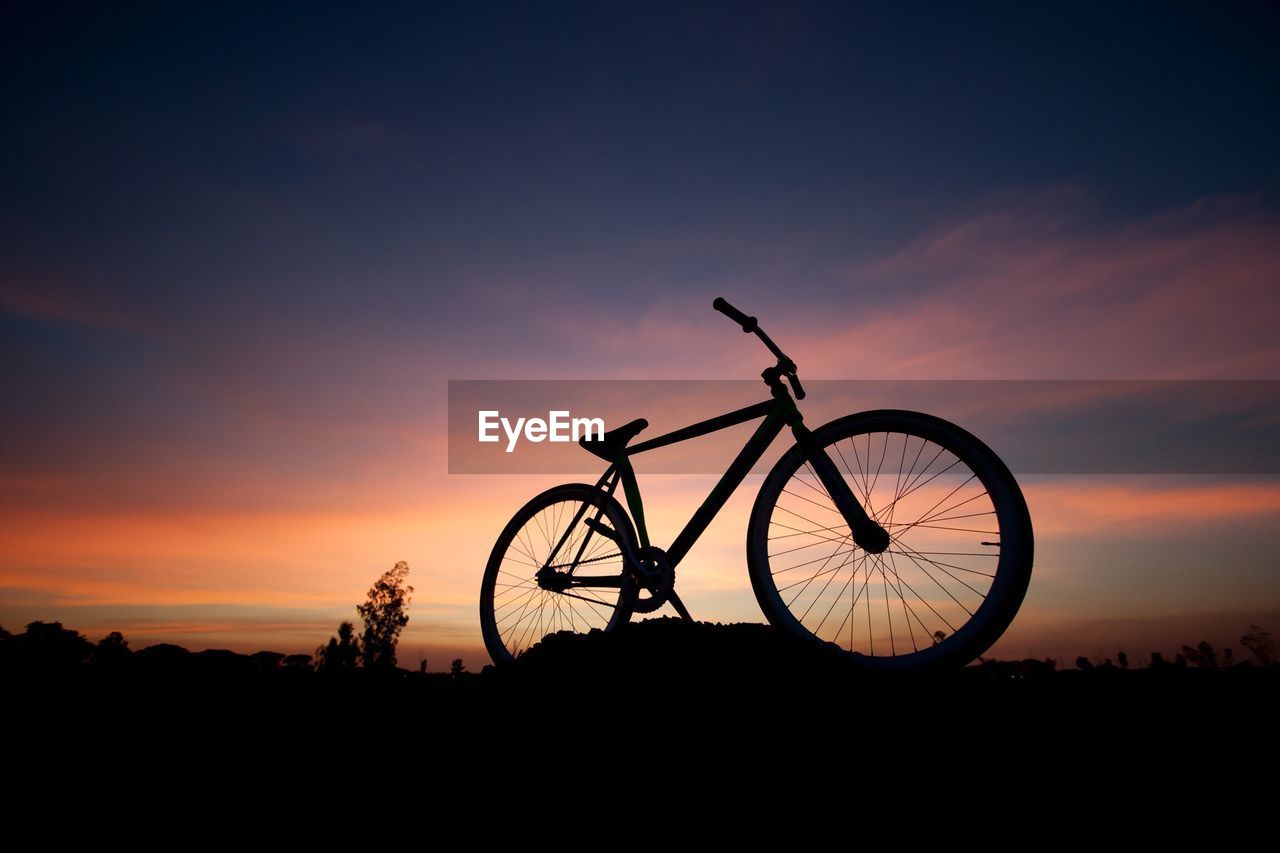 Silhouette of bicycle against sky during sunset