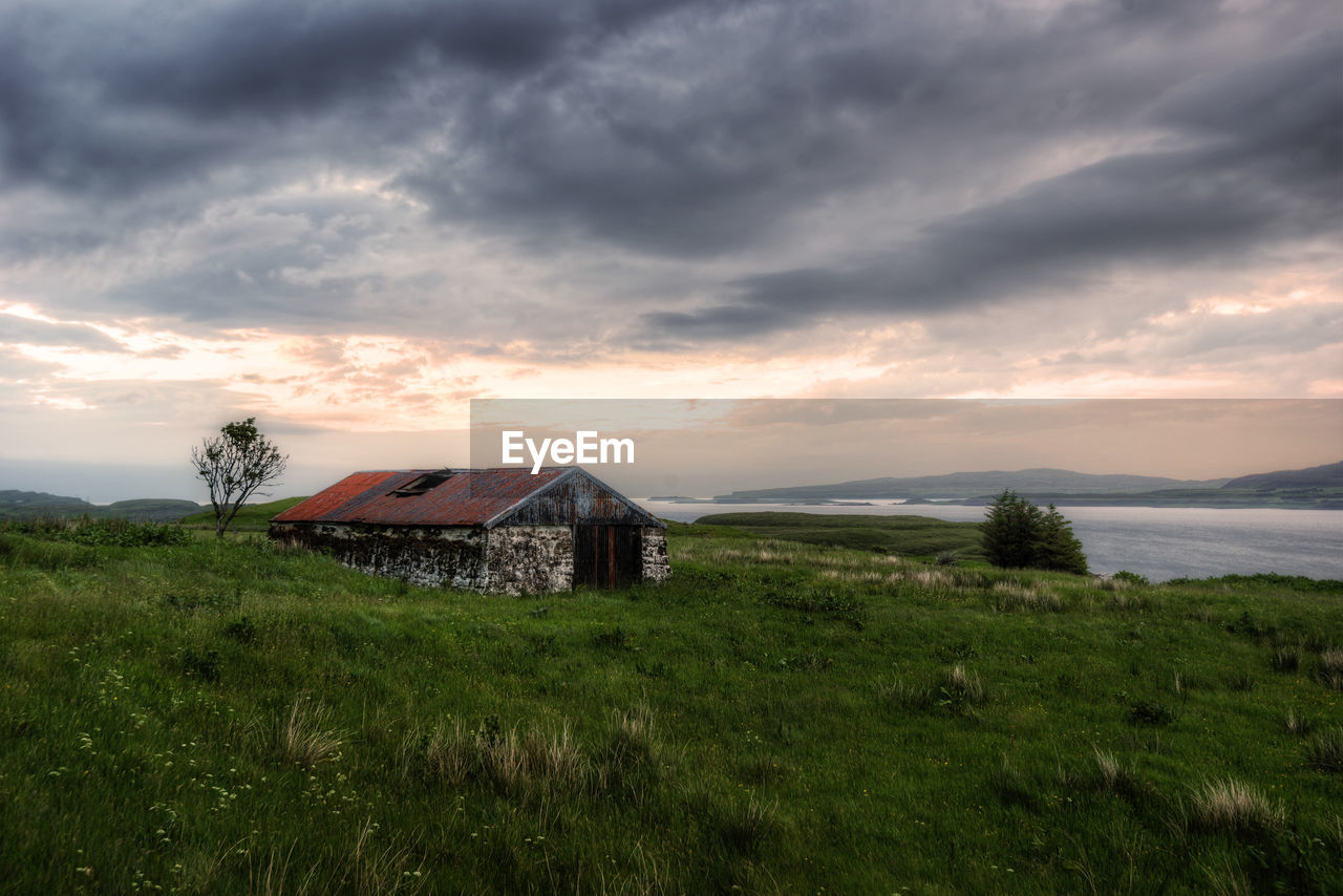 House on field against sky during sunset