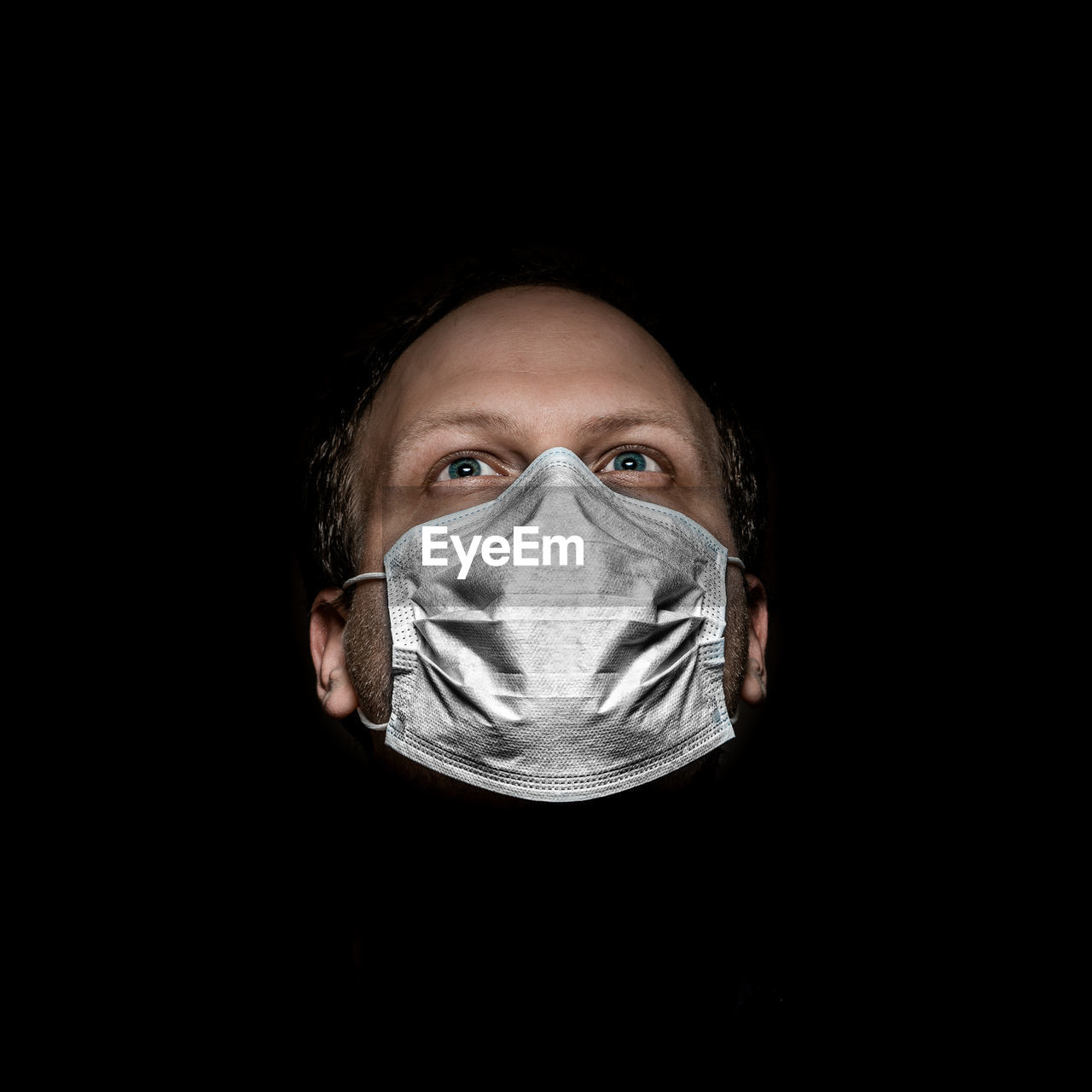 Portrait of a man with mask looking away from camera against black background