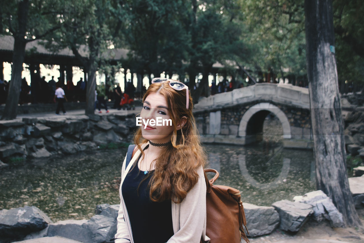 Portrait of woman standing against trees in water