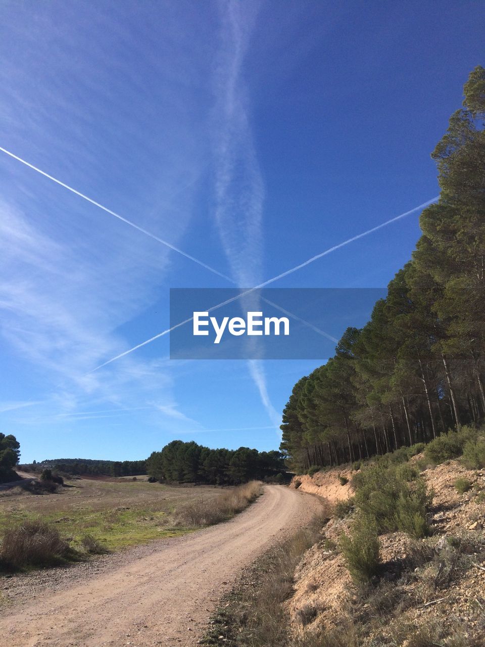 Landscape against vapor trail in sky
