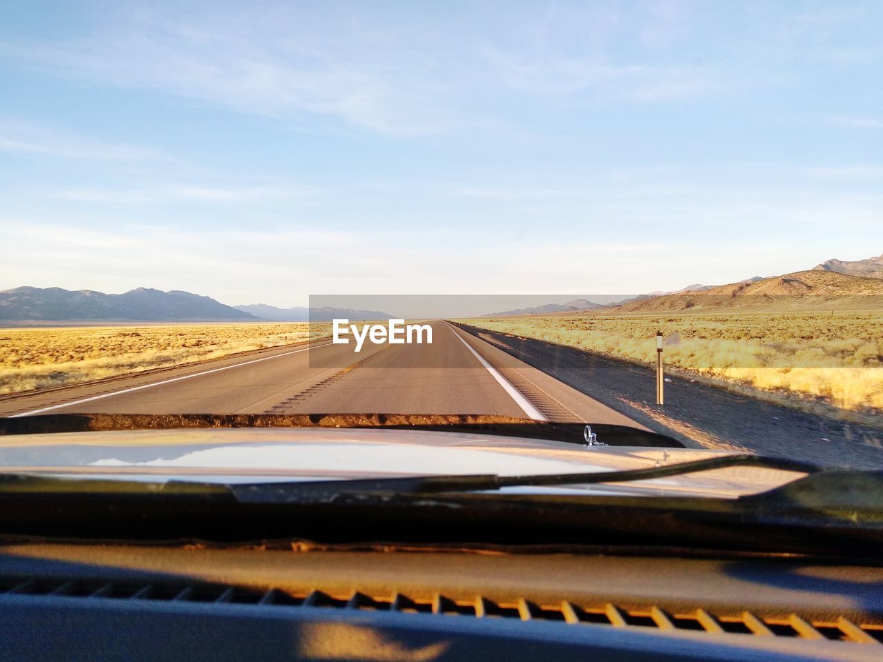 Scenic view of road against sky seen through car windshield