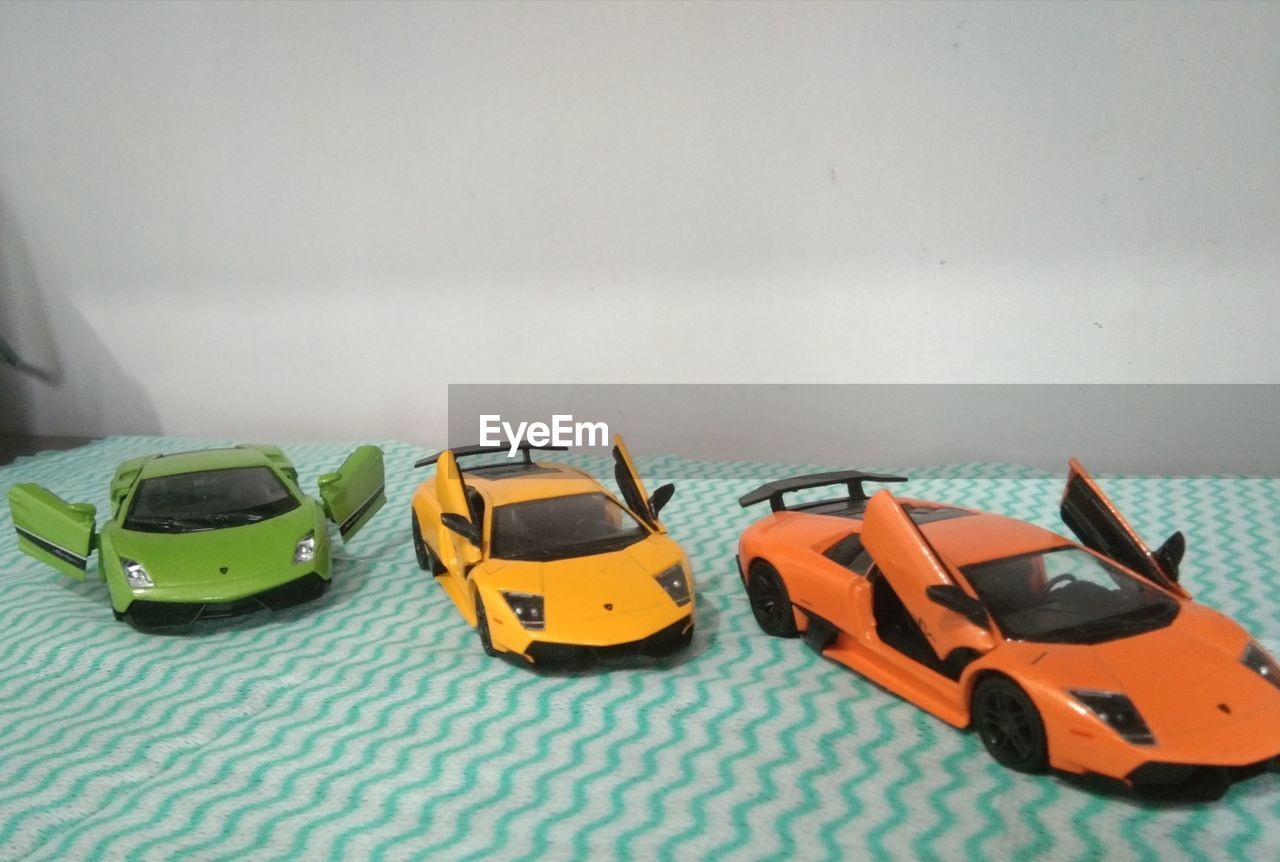 HIGH ANGLE VIEW OF VARIOUS TOY CAR AGAINST WALL