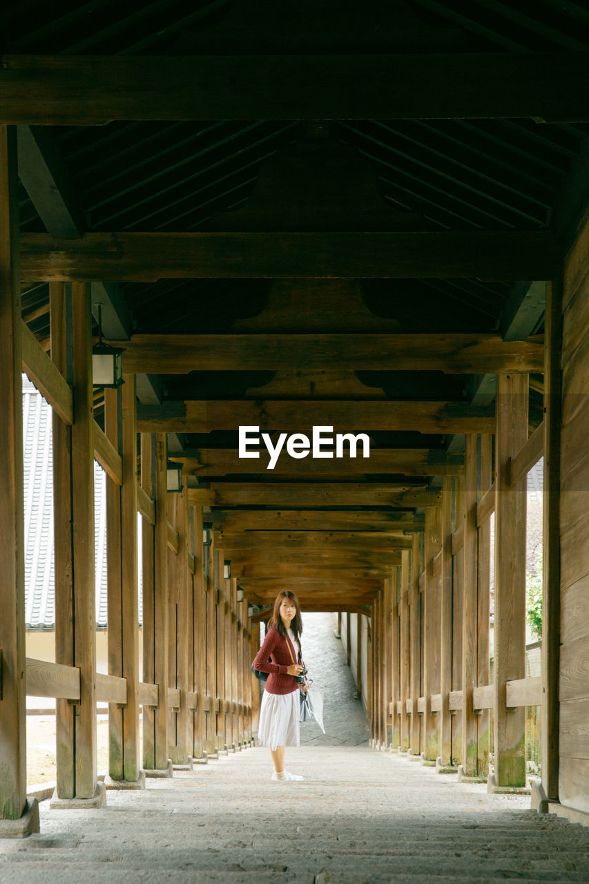 Portrait of young woman standing at colonnade