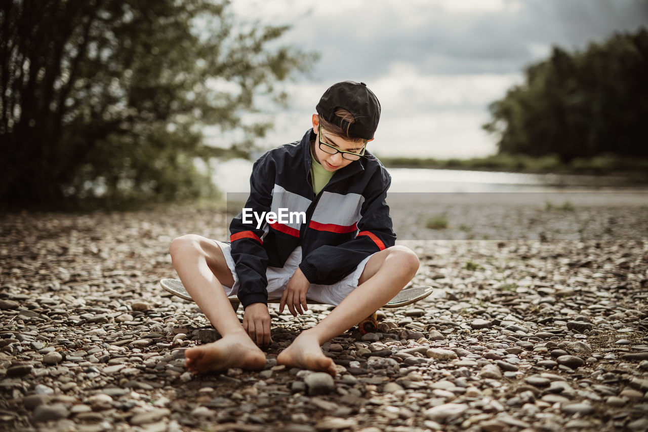 Full length of boy sitting on pebbles