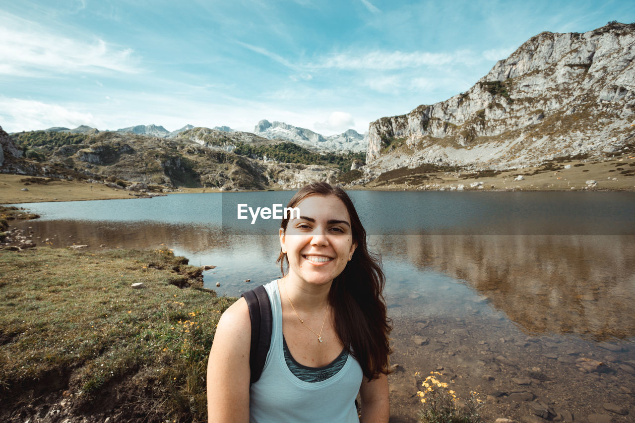 portrait of young woman standing by lake