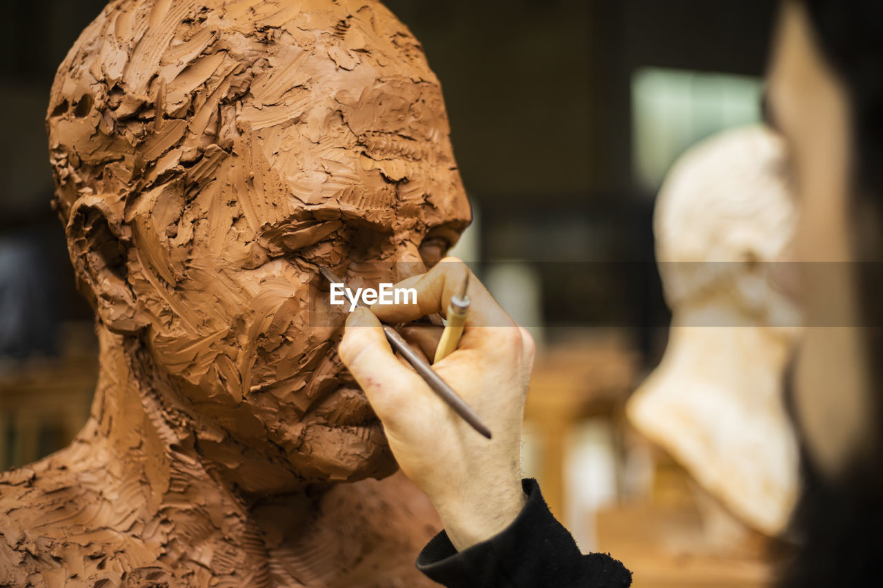 Hand of sculptor finishing a clay head eye
