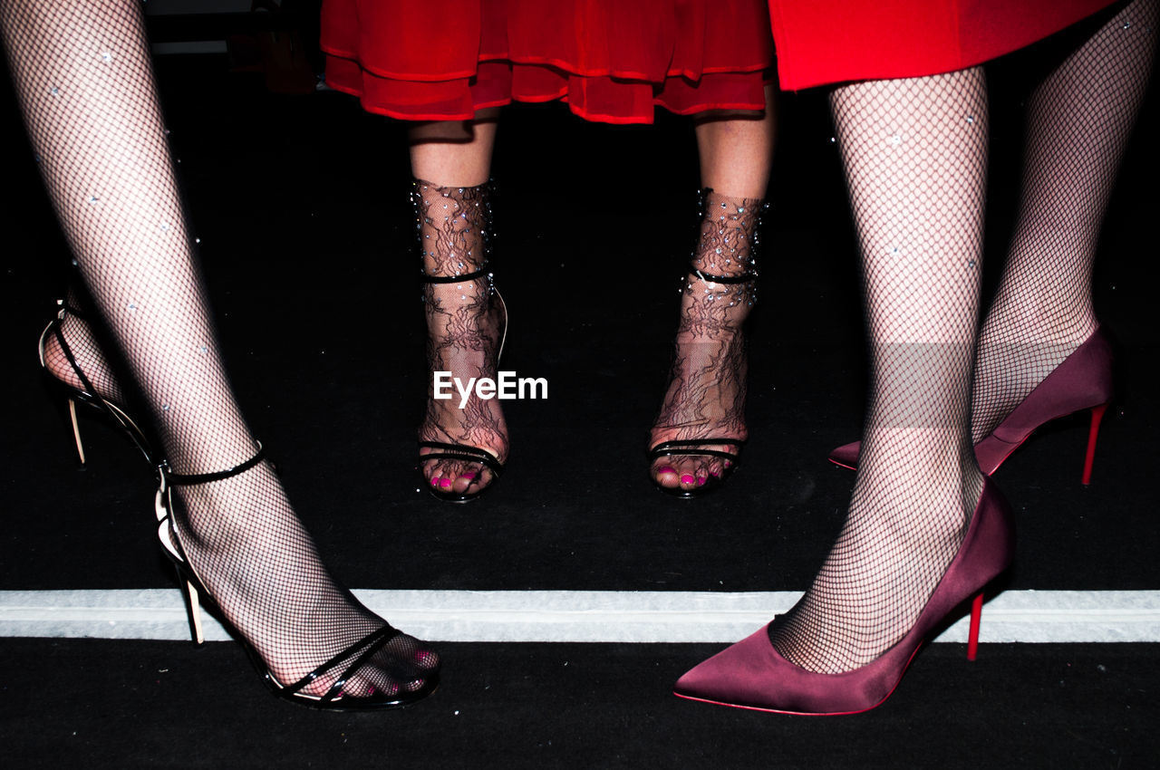 LOW SECTION OF WOMAN IN RED SHOES STANDING OUTDOORS