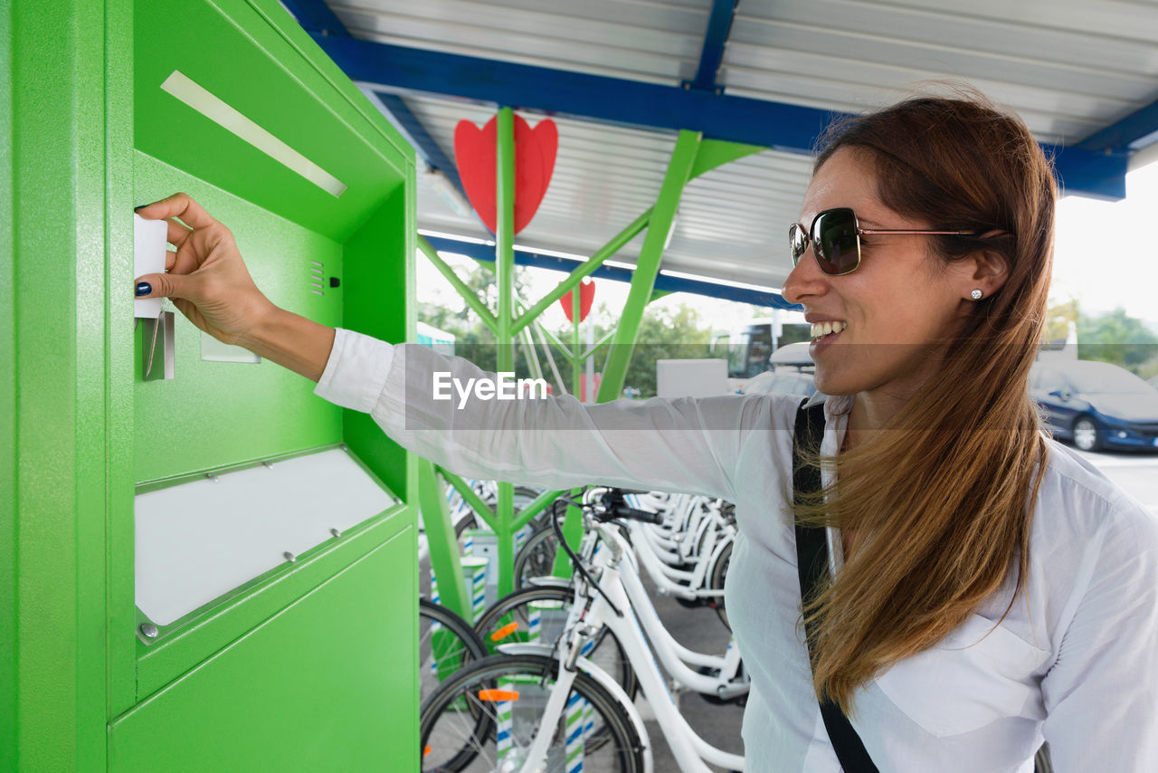 Businesswoman using machinery at bicycle sharing system