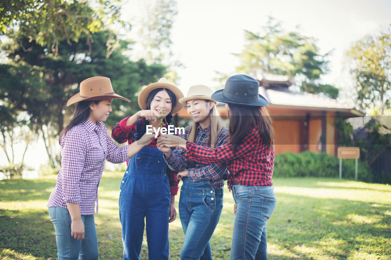 Happy female friends looking at buds while standing at park