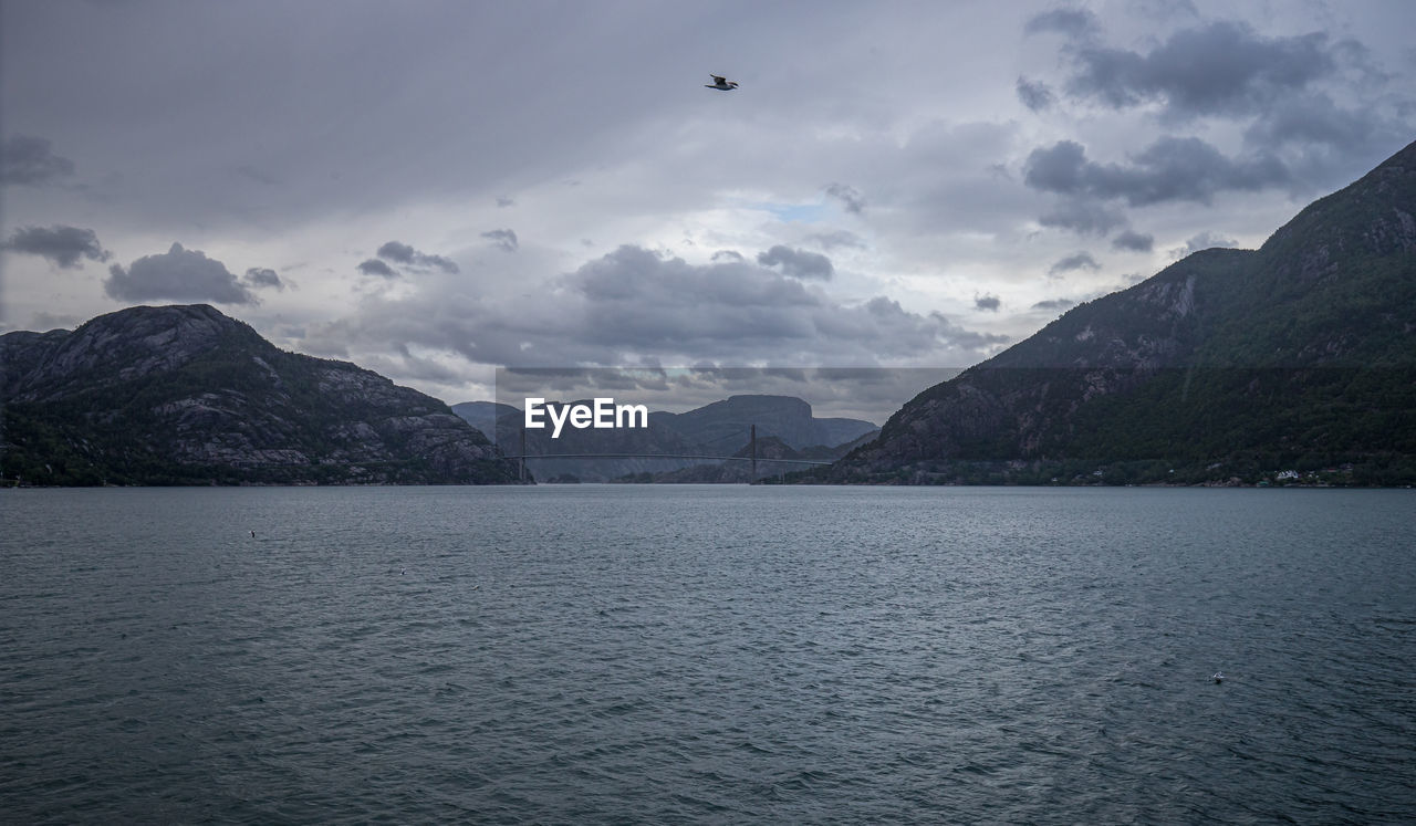 Scenic view of sea by mountains against sky