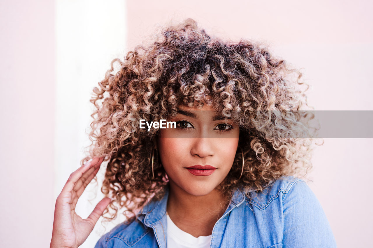 Portrait of confident serious hispanic woman with afro hair in city. spring. urban lifestyle