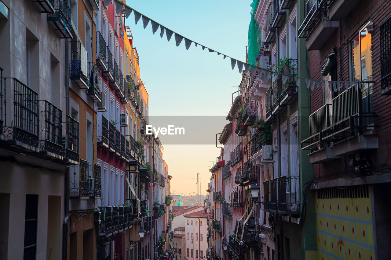 Perspective of close residential buildings with balconies and flag banner in aged city under clear sky