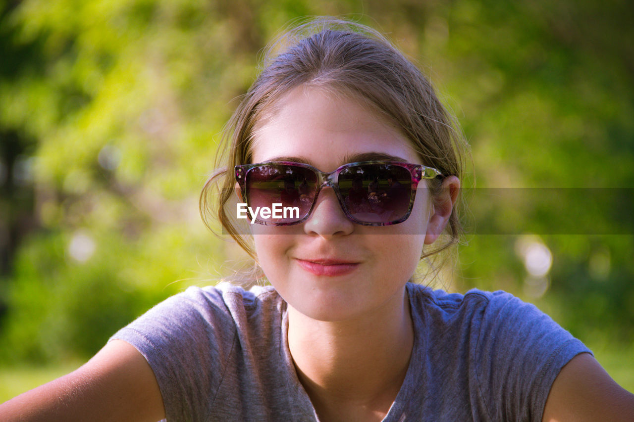 Close-up of smiling woman wearing sunglasses at park