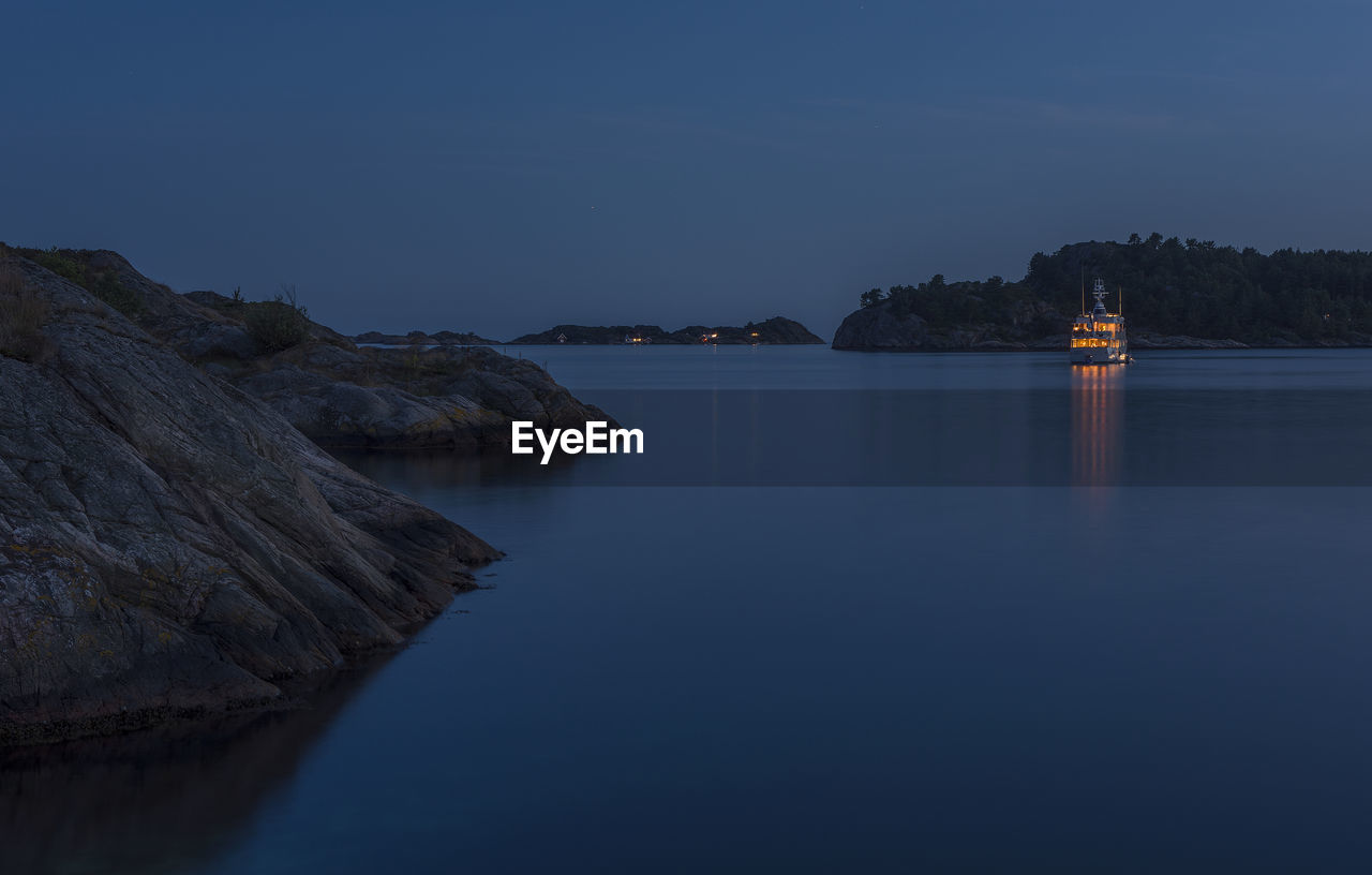 Scenic view of yacht against clear blue sky at night