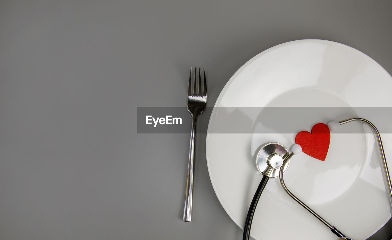 fork, kitchen utensil, eating utensil, silverware, plate, indoors, household equipment, studio shot, heart shape, food and drink, copy space, love, white, table knife, no people, food, positive emotion, emotion, red, knife, table, still life, crockery, setting, gray, spoon, empty, sparse