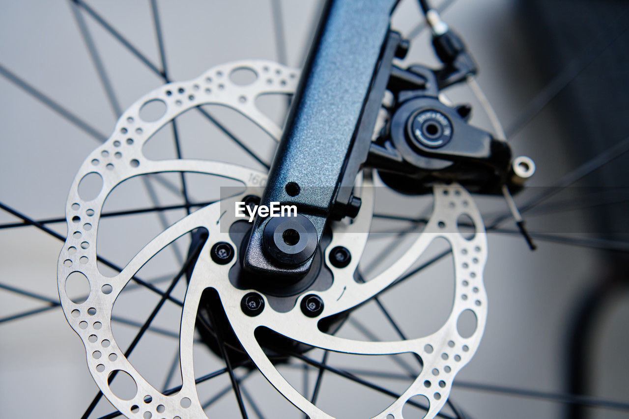 Part of the bicycle's braking system. grey metal brake disc and brake pads on road bike, close up.