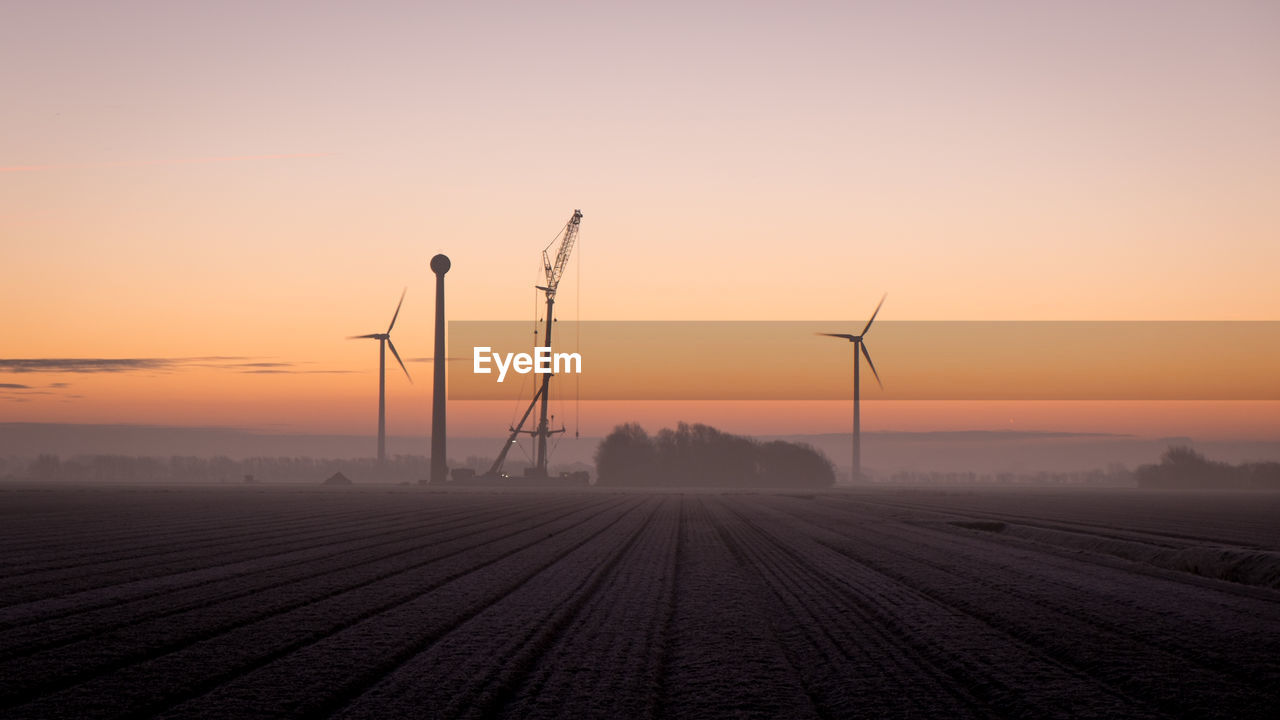 WIND TURBINES IN FIELD DURING SUNSET