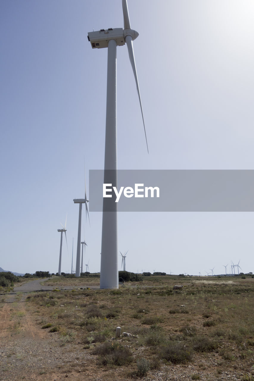 LOW ANGLE VIEW OF WINDMILLS ON FIELD AGAINST SKY