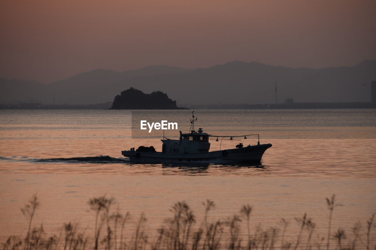 SILHOUETTE SHIP IN SEA AGAINST SUNSET SKY