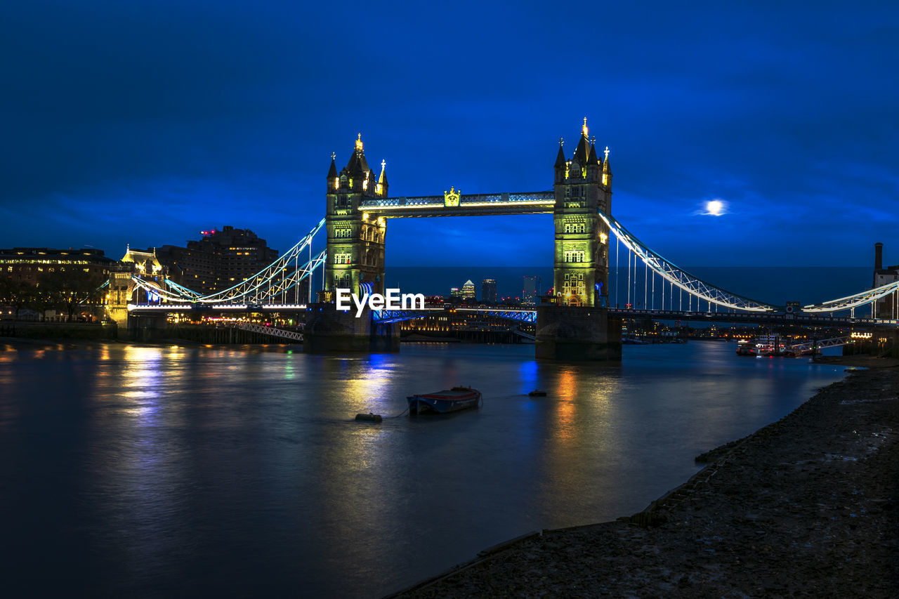 Illuminated bridge over river at night