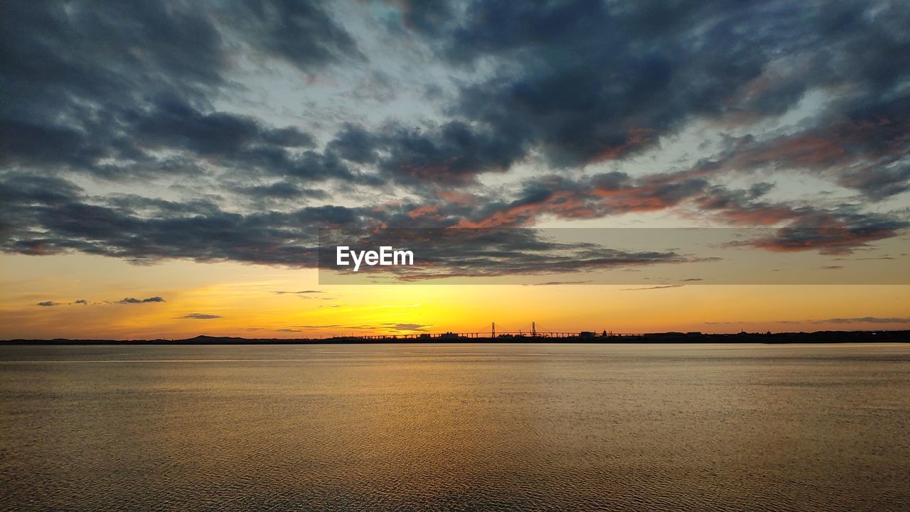 Scenic view of sea against dramatic sky during sunset