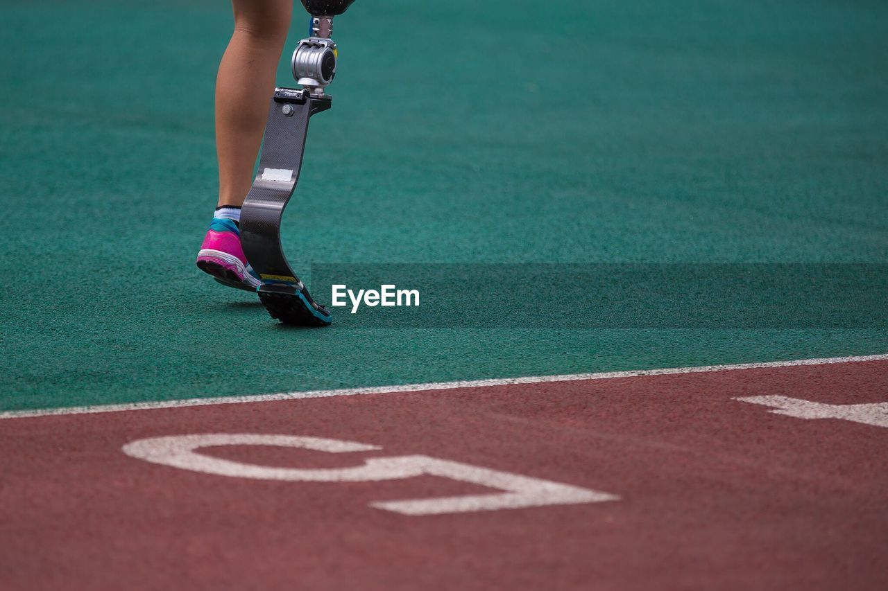 Low section of woman with artificial leg running on track