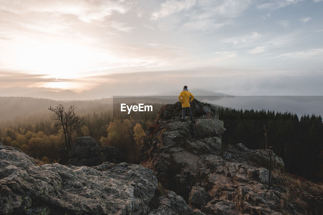 Man standing on rock against sky