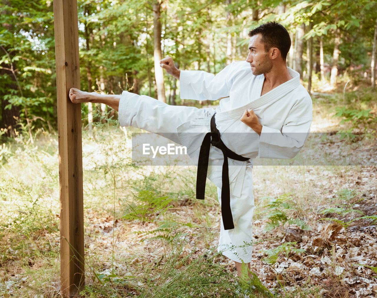 Man with karategi practicing martial arts in the forest