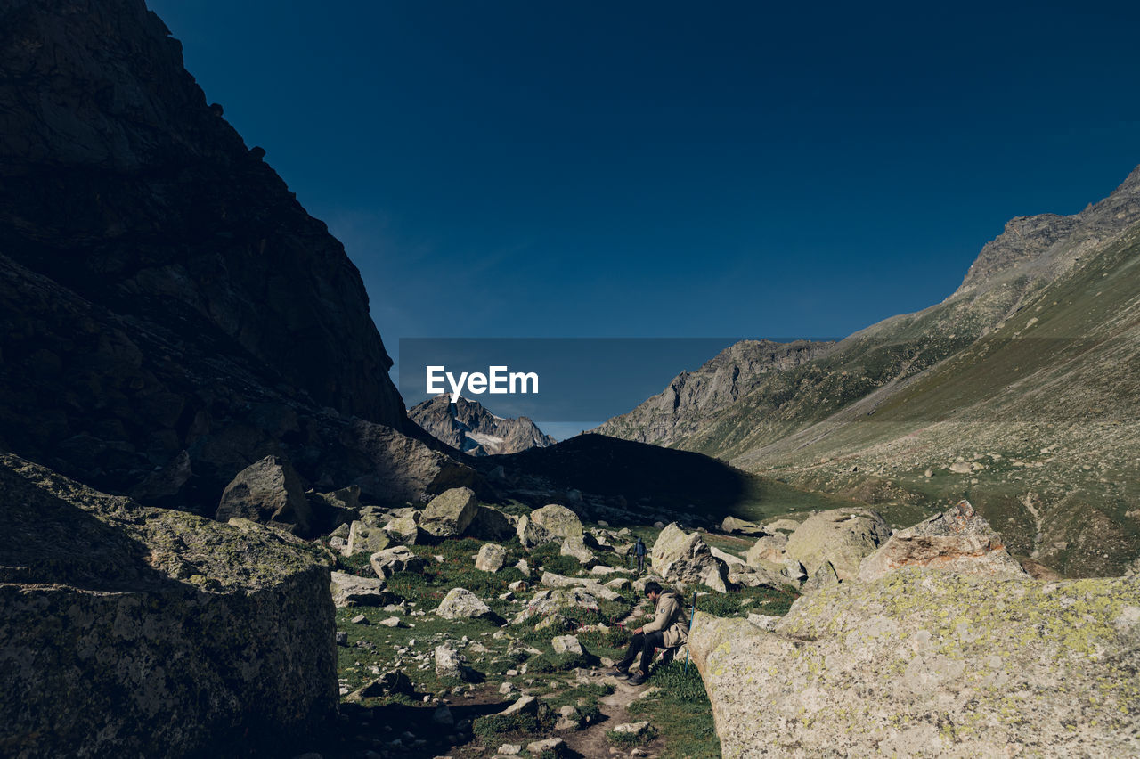 mountain, environment, scenics - nature, landscape, mountain range, sky, nature, beauty in nature, rock, land, wilderness, valley, travel destinations, no people, travel, adventure, blue, tranquility, non-urban scene, outdoors, ridge, terrain, clear sky, geology, tranquil scene, activity, sunlight, water, plateau, day, tourism, plant, sunny, mountain peak
