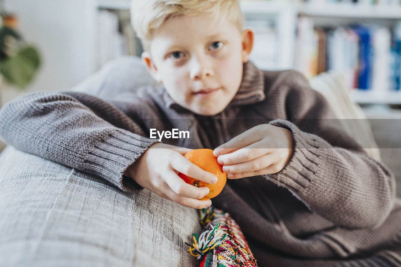 Boy peeling clementine