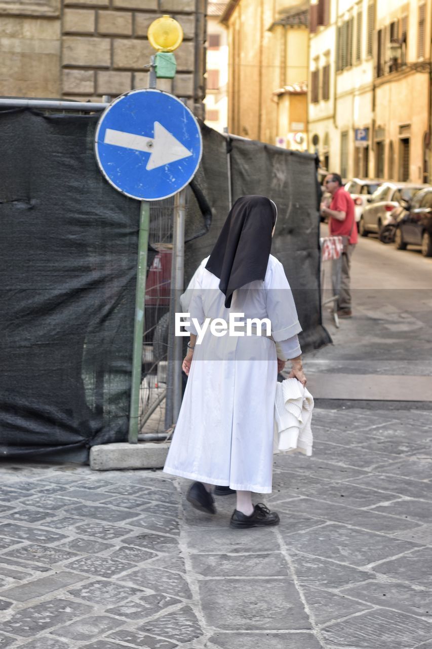 Rear view of woman walking on street amidst buildings