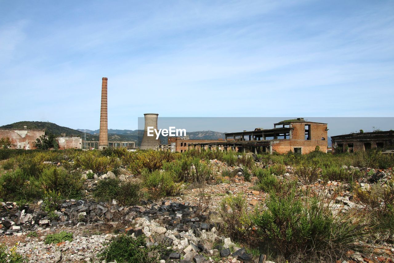 architecture, built structure, building exterior, sky, nature, ruins, plant, environment, landscape, industry, no people, building, factory, hill, outdoors, coast, smoke stack, land, landmark, history, day, blue, environmental issues, rural area, cloud, tower, the past