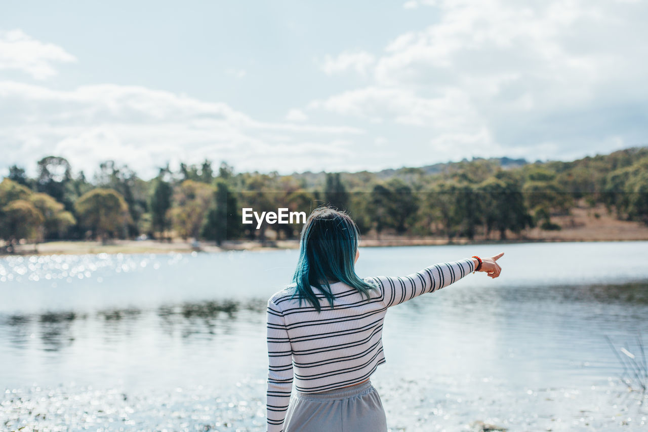 Rear view of woman pointing at lake