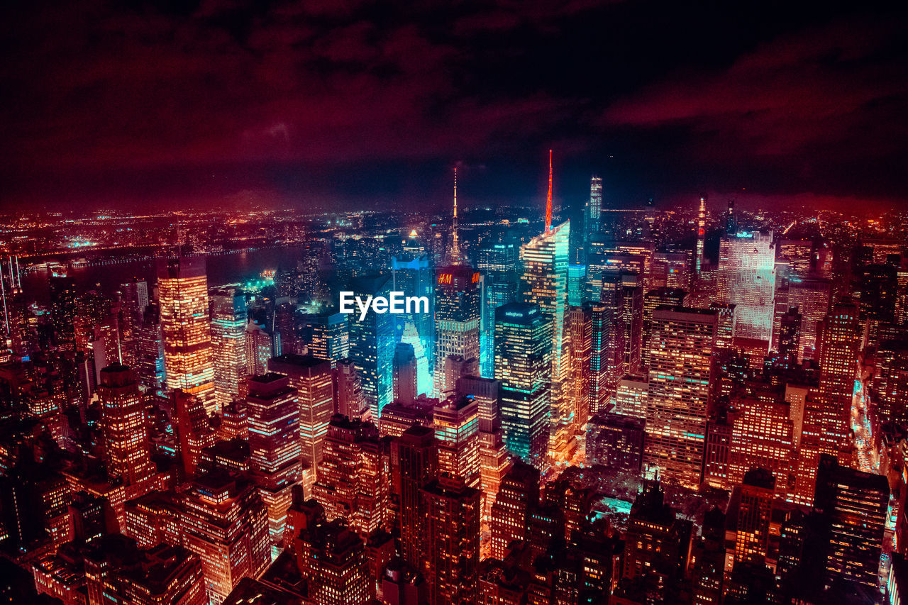 HIGH ANGLE VIEW OF ILLUMINATED BUILDINGS AGAINST SKY AT NIGHT