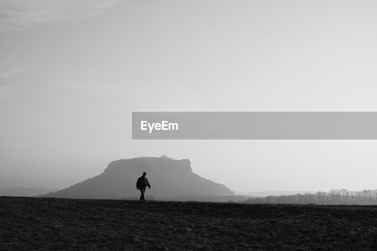 Man walking on field against clear sky